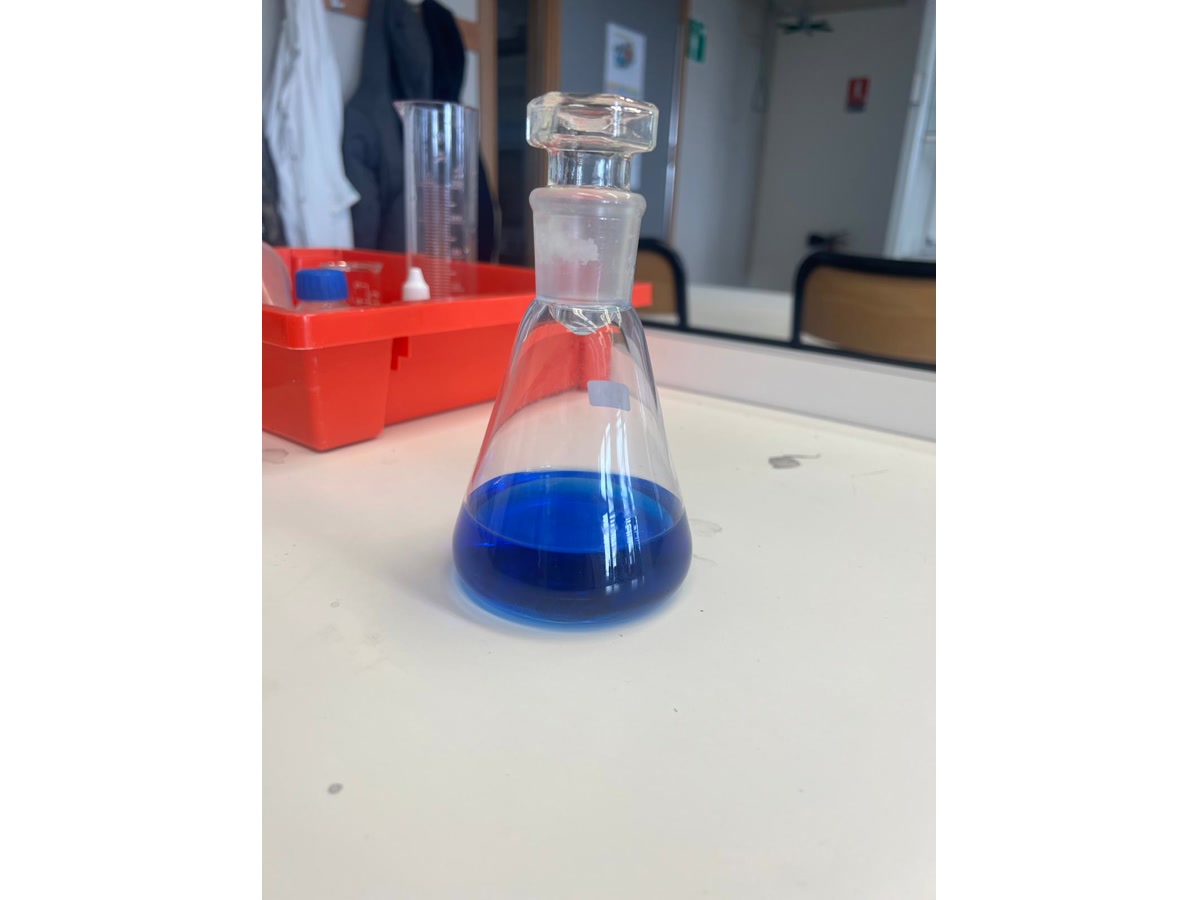 Fiole contenant une solution bleue sur une paillasse de laboratoire